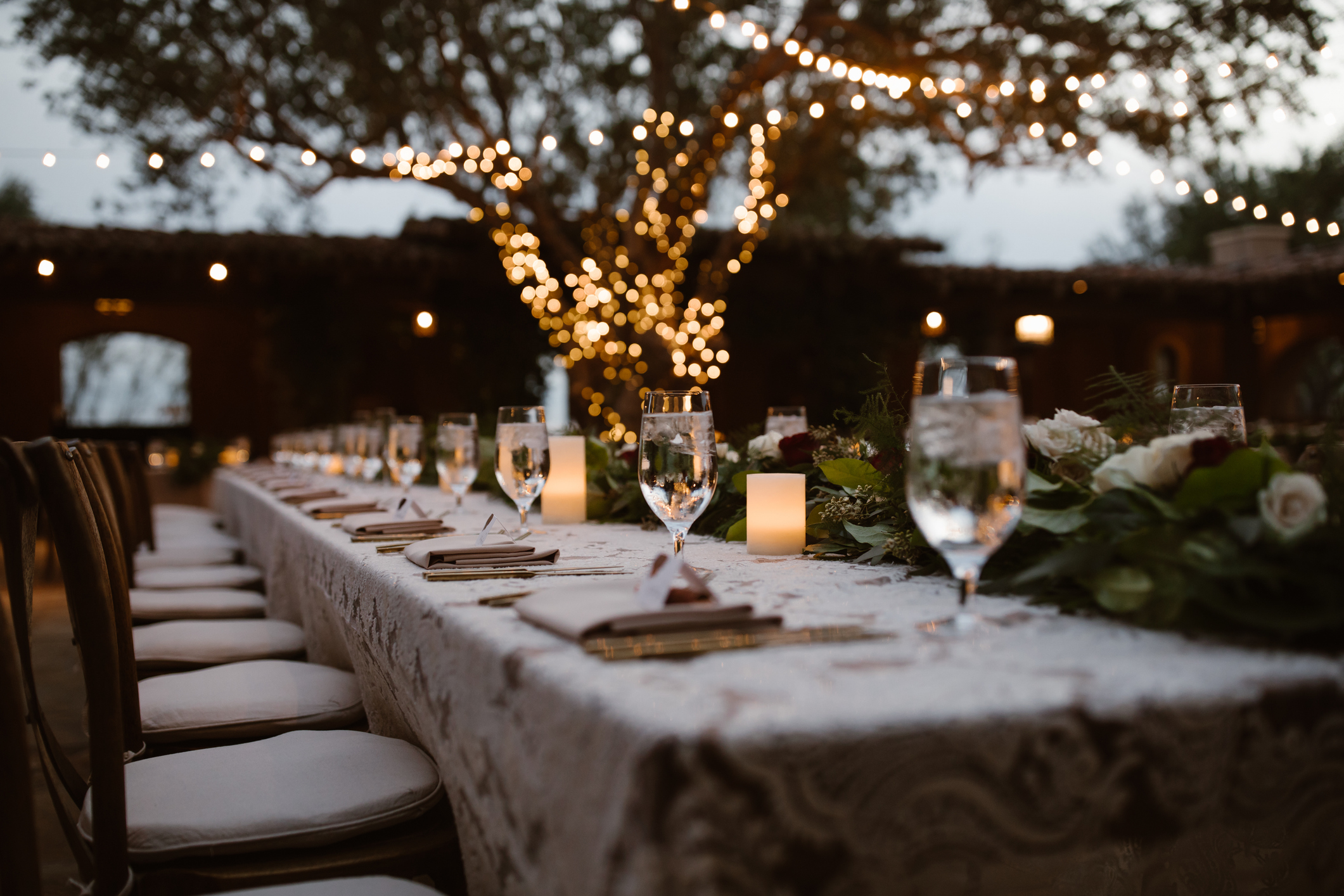 Reception table at dusk with string lights, candles, and florals